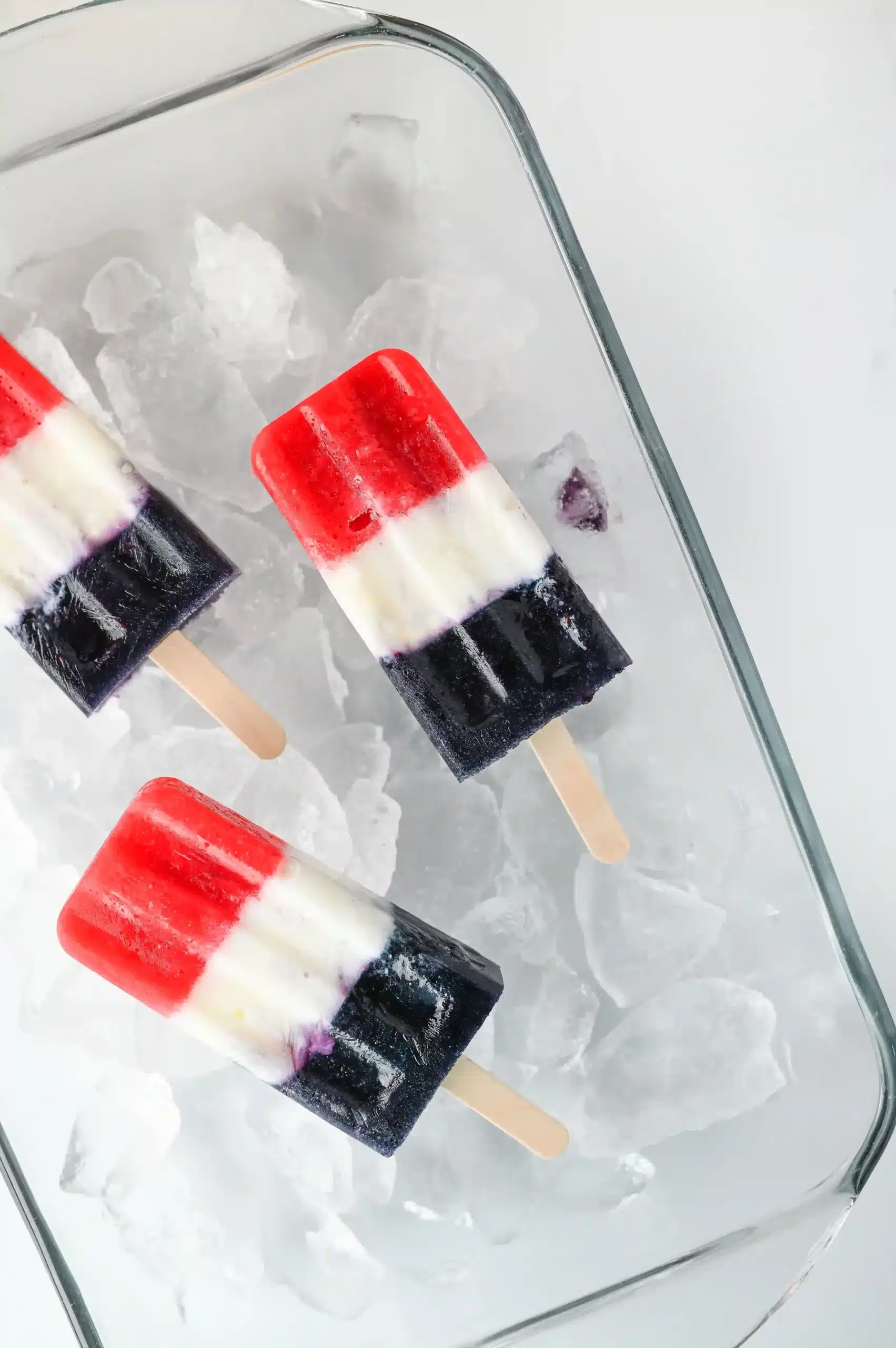 red white and blue popsicles in a container of ice