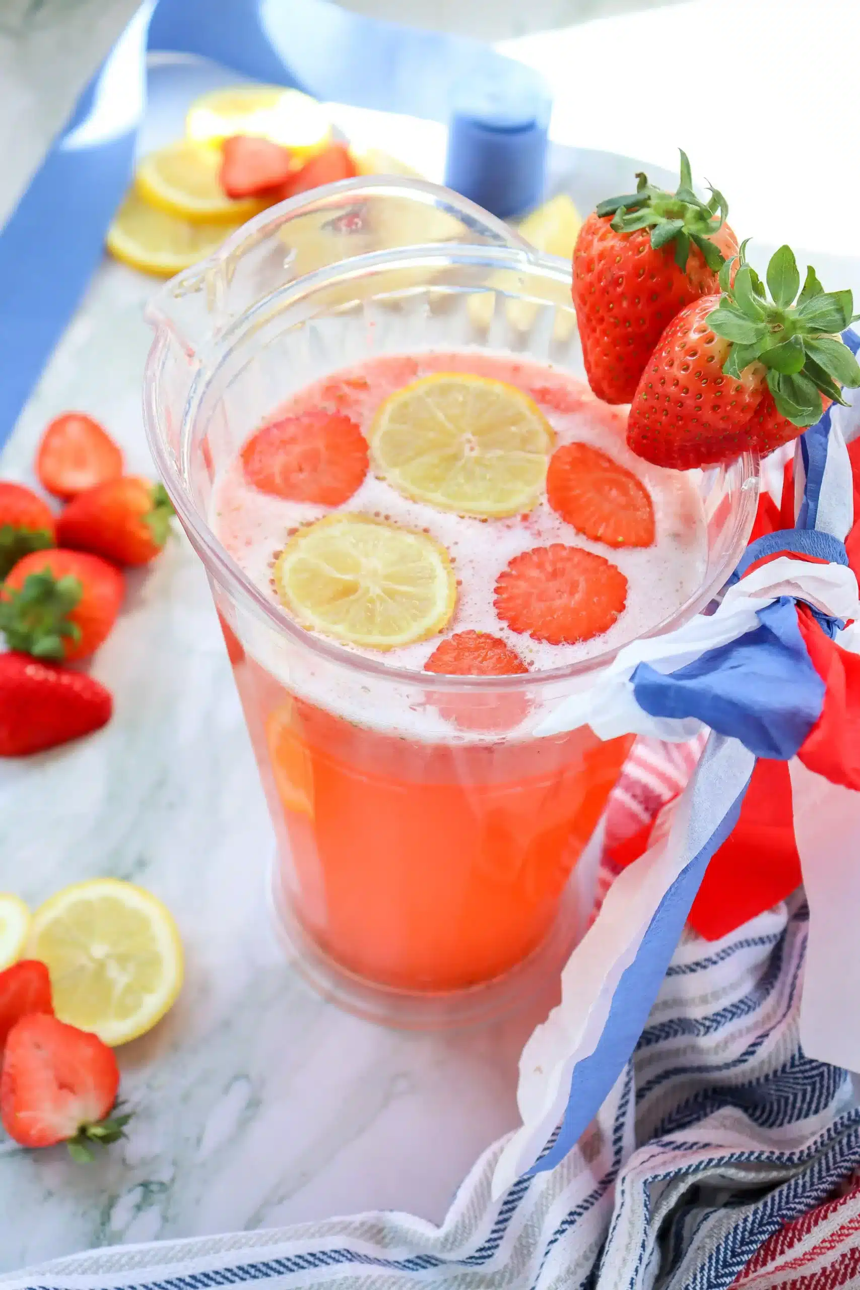 strawberry lemonade in a pitcher with cut lemons and strawberries